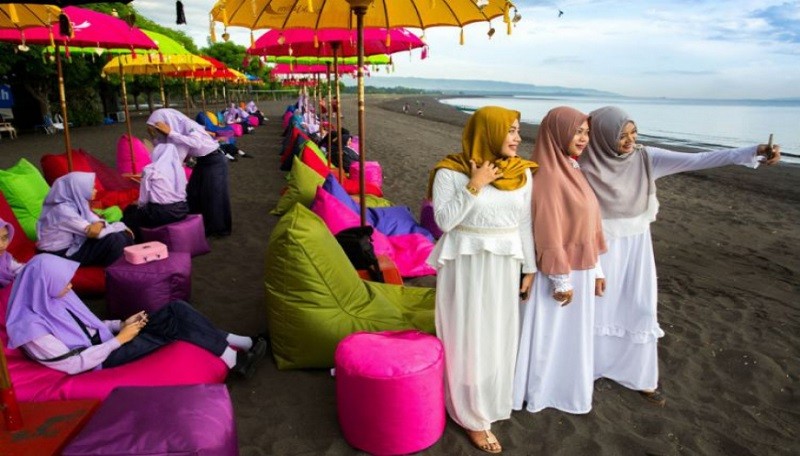 Wisatawan Muslim sedang berada di pinggir pantai Kuta, Bali (Ilustrasi)