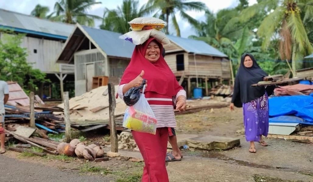 Warga tersenyum usai menerima bantuan paket pangan dari para dermawan. (Foto: ACT)