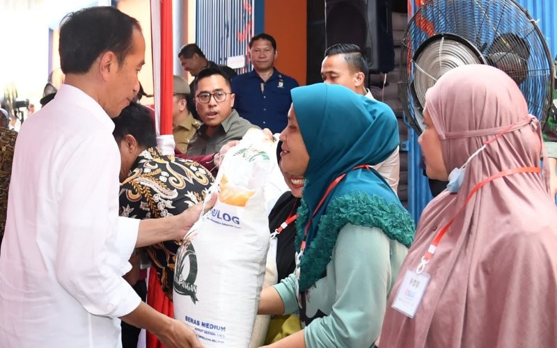 Presiden Joko Widodo menyerahkan bantuan pangan kepada keluarga penerima manfaat (KPM) di Gudang Bulog Sukamaju, Kota Palembang (Setkab)