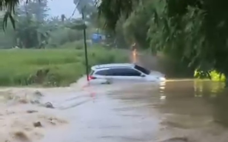 Sebuah mobil terseret arus saat nekat menerobos banjir di Situ Kampung Nawit, Bekasi, Jawa Barat.