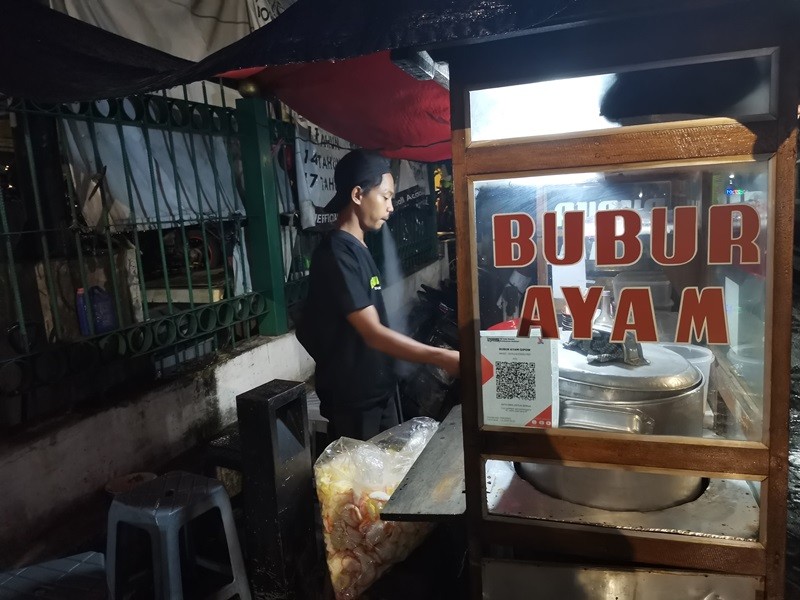 Tukang bubur ayam sudah menggunakan layanan QRIS BRI untuk mempermudah transaksi pembayaran. (foto: Ibnu/IDXChannel)