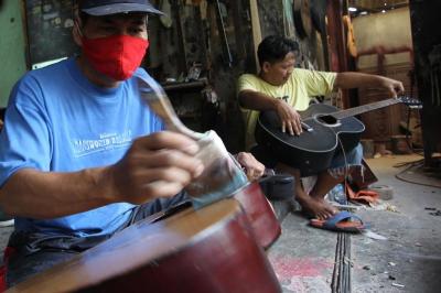 Pekerja menyelesaikan pembuatan gitar di sentra produksi dan reparasi gitar Pak Manto, Jalan Langgar II, Pejaten Timur, Pasar Minggu, Jakarta Selatan, Minggu (7