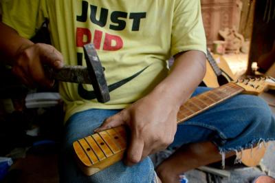 Pekerja menyelesaikan pembuatan gitar di sentra produksi dan reparasi gitar Pak Manto, Jalan Langgar II, Pejaten Timur, Pasar Minggu, Jakarta Selatan, Minggu (7