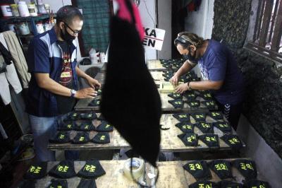 Pekerja membuat masker bersablon di Punya Ku sablon di kawasan Pondok Melati, Kota Bekasi, Jawa Barat, Sabtu (13/3/2021).