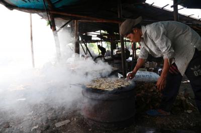 Perajin melakukan pengasapan ikan jenis patin di kawasan pesisir Kenjeran Surabaya, Jawa Timur, Kamis (18/3/2021).