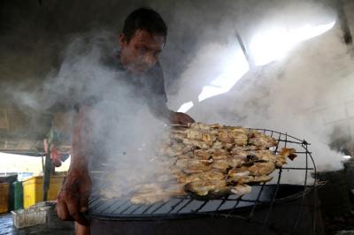 Perajin melakukan pengasapan ikan jenis patin di kawasan pesisir Kenjeran Surabaya, Jawa Timur, Kamis (18/3/2021).