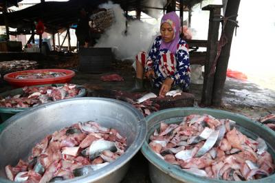 Perajin membersihkan ikan jenis patin di kawasan pesisir Kenjeran Surabaya, Jawa Timur, Kamis (18/3/2021).