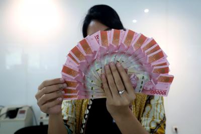 Karyawan menunjukkan uang rupiah di salah satu Kantor Cabang Bank DKI, Jakarta, Jumat (26/3/2021).