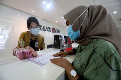 Karyawan menunjukkan uang rupiah di salah satu Kantor Cabang Bank DKI, Jakarta, Jumat (26/3/2021).