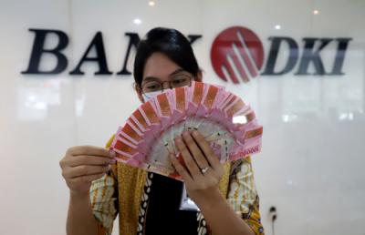 Karyawan menunjukkan uang rupiah di salah satu Kantor Cabang Bank DKI, Jakarta, Jumat (26/3/2021).