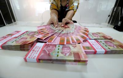 Karyawan menunjukkan uang rupiah di salah satu Kantor Cabang Bank DKI, Jakarta, Jumat (26/3/2021).