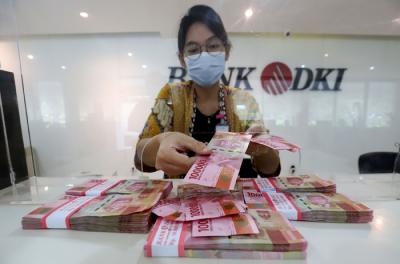 Karyawan menunjukkan uang rupiah di salah satu Kantor Cabang Bank DKI, Jakarta, Jumat (26/3/2021).