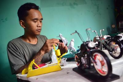 Pengrajin Andriatna Marbela menyelesaikan pesanan miniatur motor custom dari limbah plastik di Kemang, Bogor, Jawa Barat, Sabtu (27/3/2021).
