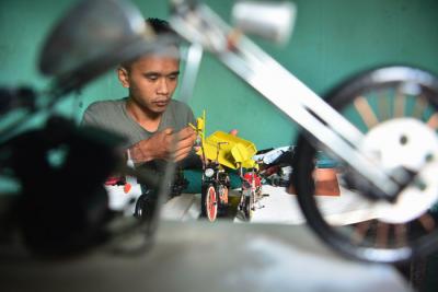 Pengrajin Andriatna Marbela menyelesaikan pesanan miniatur motor custom dari limbah plastik di Kemang, Bogor, Jawa Barat, Sabtu (27/3/2021).