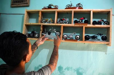 Pengrajin Andriatna Marbela menyelesaikan pesanan miniatur motor custom dari limbah plastik di Kemang, Bogor, Jawa Barat, Sabtu (27/3/2021).