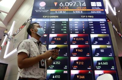 Pengunjung melintasi layar bursa saham di Bursa Efek Indonesia (BEI), Jakarta, Selasa (30/3/2021).
