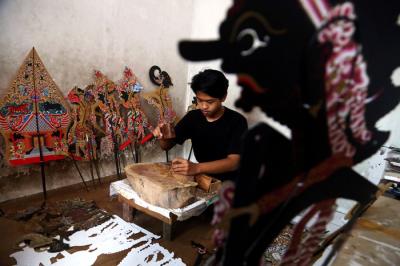 Perajin wayang Ahmad Maiyo Satria Tama (16) menyelesaikan pembuatan dan perbaikan wayang di Surabaya, Jawa Timur, Rabu (31/3/2021).