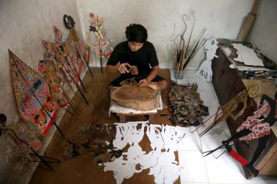 Perajin wayang Ahmad Maiyo Satria Tama (16) menyelesaikan pembuatan dan perbaikan wayang di Surabaya, Jawa Timur, Rabu (31/3/2021).