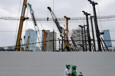 Warga melintasi proyek pembangunan gedung di Jakarta Pusat, Senin (5/4/2021).