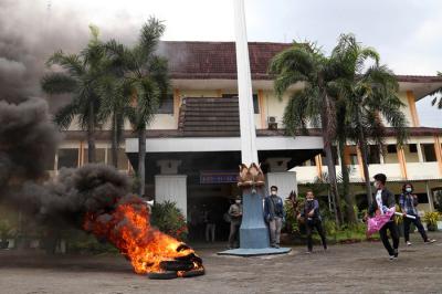 Mahasiswa meluapkan emosi dengan membakar ban bekas saat melakukan aksi demonstrasi didepan kampus Universitas DR. Soetomo (Unitomo) Surabaya, Kamis (8/4/2021).