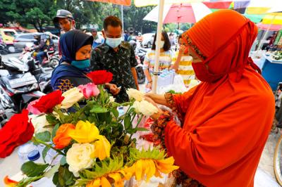 Pedagang bunga tabur melayani warga yang berbelanja bunga dan air mawar di pintu masuk TPU Karet Bivak, Jakarta, Minggu (11/4/2021).