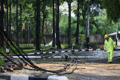 Petugas kepolisian dan PLN meninjau lokasi pohon tumbang di Jalan Hang Tuah Raya, Kebayoran Baru, Jakarta Selatan, Rabu (14/4/2021).