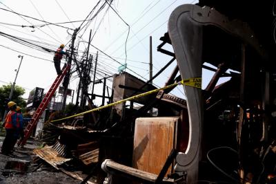 Petugas PLN memperbaiki jaringan listrik yang terputus pasca kebakaran bengkel mebel di Jalan Semolowaru, Surabaya, Kamis (15/4/2021).