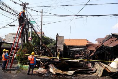 Petugas PLN memperbaiki jaringan listrik yang terputus pasca kebakaran bengkel mebel di Jalan Semolowaru, Surabaya, Kamis (15/4/2021).