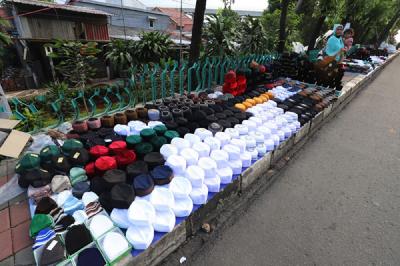 Penjual merapikan peci di kawasan Cillitan, Jakarta Timur, Selasa (20/4/2021).