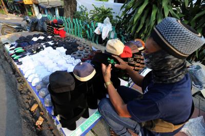 Penjual merapikan peci di kawasan Cillitan, Jakarta Timur, Selasa (20/4/2021).