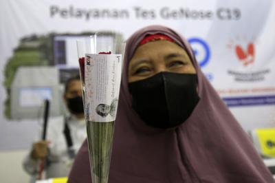 Petugas KAI dengan mengenakan pakaian kebaya memberikan bunga kepada penumpang di Stasiun Gambir, Jakarta, Rabu (21/4/2021).