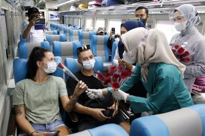 Petugas KAI dengan mengenakan pakaian kebaya memberikan bunga kepada penumpang di Stasiun Gambir, Jakarta, Rabu (21/4/2021).