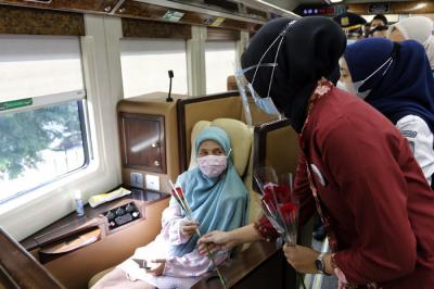 Petugas KAI dengan mengenakan pakaian kebaya memberikan bunga kepada penumpang di Stasiun Gambir, Jakarta, Rabu (21/4/2021).