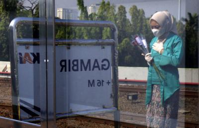Petugas KAI dengan mengenakan pakaian kebaya memberikan bunga kepada penumpang di Stasiun Gambir, Jakarta, Rabu (21/4/2021).