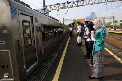 Petugas KAI dengan mengenakan pakaian kebaya memberikan bunga kepada penumpang di Stasiun Gambir, Jakarta, Rabu (21/4/2021).