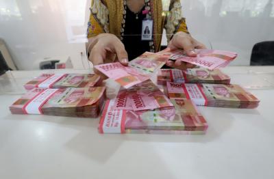 Petugas merapikan uang rupiah di salah satu bank di Jakarta, Kamis (22/4/2021).