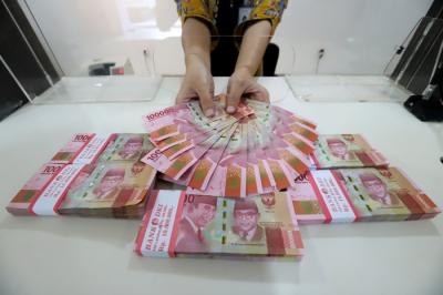 Petugas merapikan uang rupiah di salah satu bank di Jakarta, Kamis (22/4/2021).
