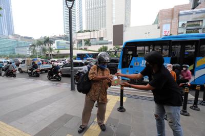 Pewarta Foto membagikan takjil kepada pejalan kaki di Kawasan Bundaran HI, Jakarta, Jumat (23/4/2021).