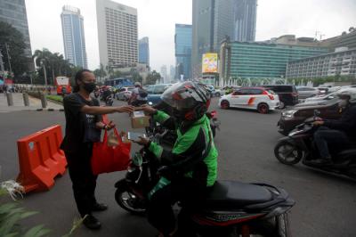 Pewarta Foto membagikan takjil kepada pejalan kaki di Kawasan Bundaran HI, Jakarta, Jumat (23/4/2021).