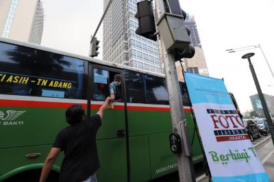 Pewarta Foto membagikan takjil kepada pejalan kaki di Kawasan Bundaran HI, Jakarta, Jumat (23/4/2021).