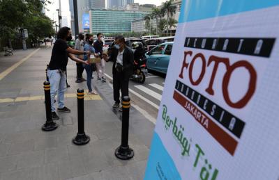 Pewarta Foto membagikan takjil kepada pejalan kaki di Kawasan Bundaran HI, Jakarta, Jumat (23/4/2021).