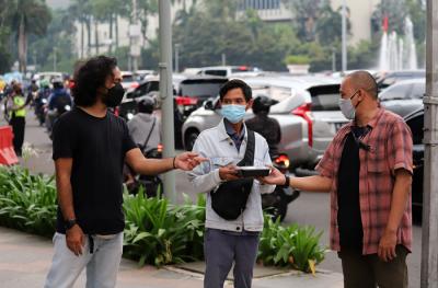 Pewarta Foto membagikan takjil kepada pejalan kaki di Kawasan Bundaran HI, Jakarta, Jumat (23/4/2021).