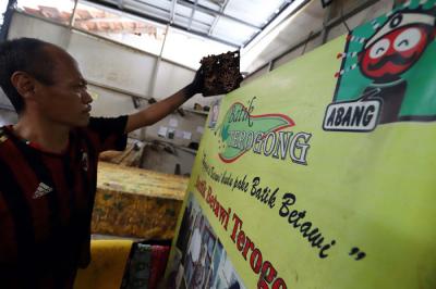 Pekerja menyelesaikan pewarnaan batik di lokasi pembuatan batik terogong khas betawi di Jakarta, Selasa (27/4/2021).
