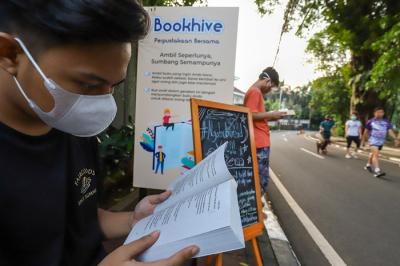 Warga membaca buku di rak buku Bookhive di kawasan Taman Situ Lembang, Menteng, Jakarta Pusat, Senin (26/4/2021).