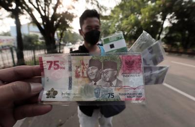 Penjual jasa penukaran uang menawarkan uang baru Rp75 ribu di kawasan Taman Mini Indonesia Indah, Jakarta Timur, Jumat (30/4/2021).