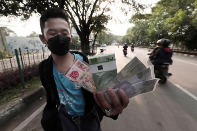 Penjual jasa penukaran uang menawarkan uang baru Rp75 ribu di kawasan Taman Mini Indonesia Indah, Jakarta Timur, Jumat (30/4/2021).