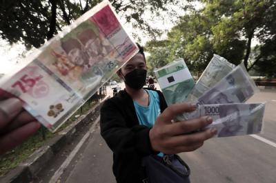 Penjual jasa penukaran uang menawarkan uang baru Rp75 ribu di kawasan Taman Mini Indonesia Indah, Jakarta Timur, Jumat (30/4/2021).