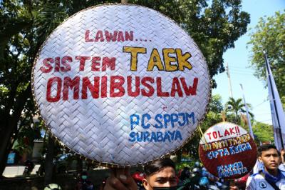 Buruh membentangkan poster bergambar Semaoen dan Marsinah saat aksi May Day didepan kantor Disnakertrans Provinsi Jawa Timur, Sabtu (1/5/2021).