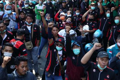 Buruh membentangkan poster bergambar Semaoen dan Marsinah saat aksi May Day didepan kantor Disnakertrans Provinsi Jawa Timur, Sabtu (1/5/2021).