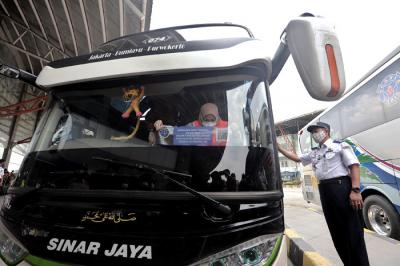 Petugas memasang stiker khusus pada armada bus yang diperbolehkan beroperasi saat masa larangan arus mudik di Terminal Pulo Gebang, Jakarta, Selasa (4/5/2021).
